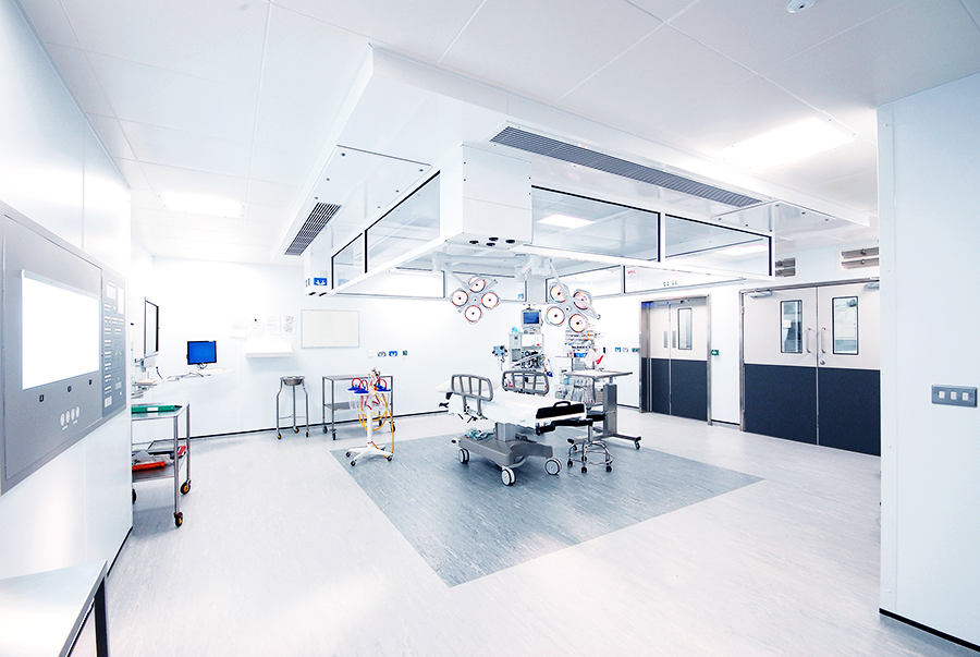 A well lit room with a hospital bed and medical equipment inside it.