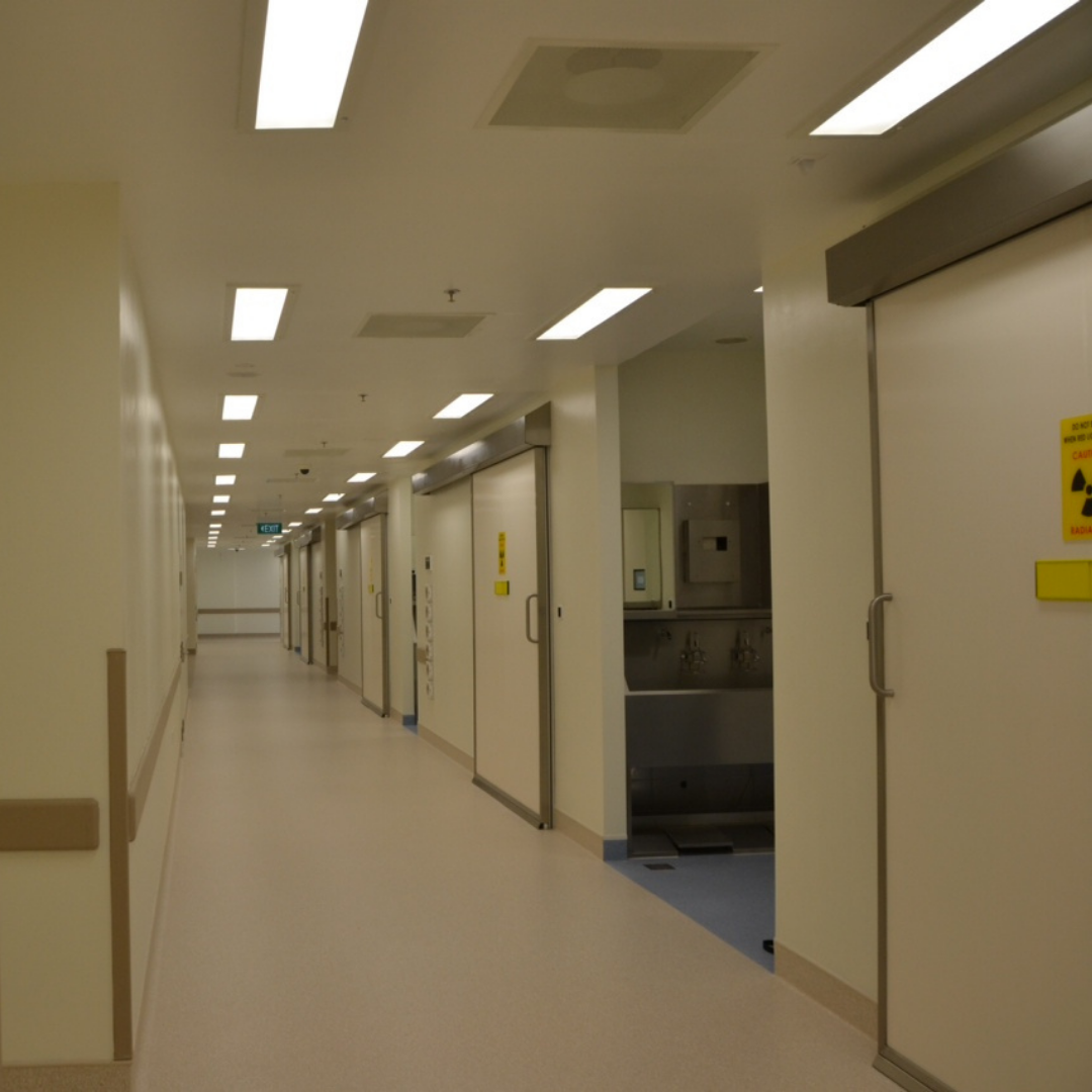 A long hospital corridor featuring lots of x-ray doors.