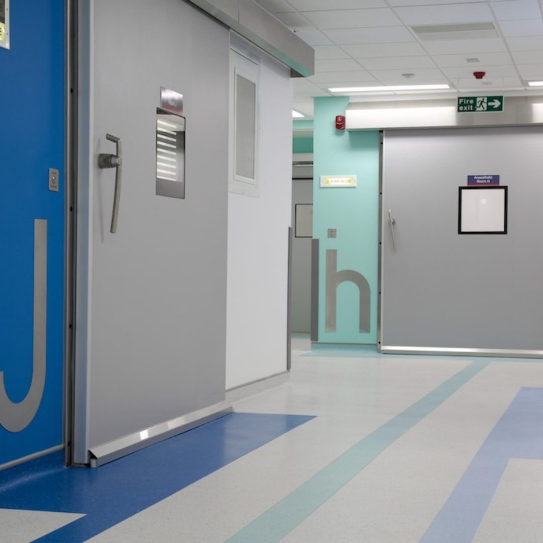 Hospital corridor with hermetic sealing hinged doors present.