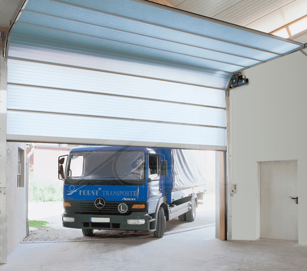 A blue van driving under a Butzbach Sectiolite Door.