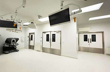 Operating room with 3 doors and tv screens.